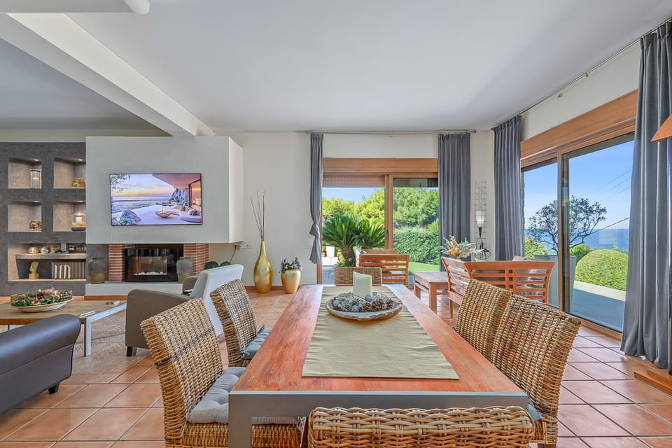The Charis open-plan dining and living area with a brick fireplace and sea views