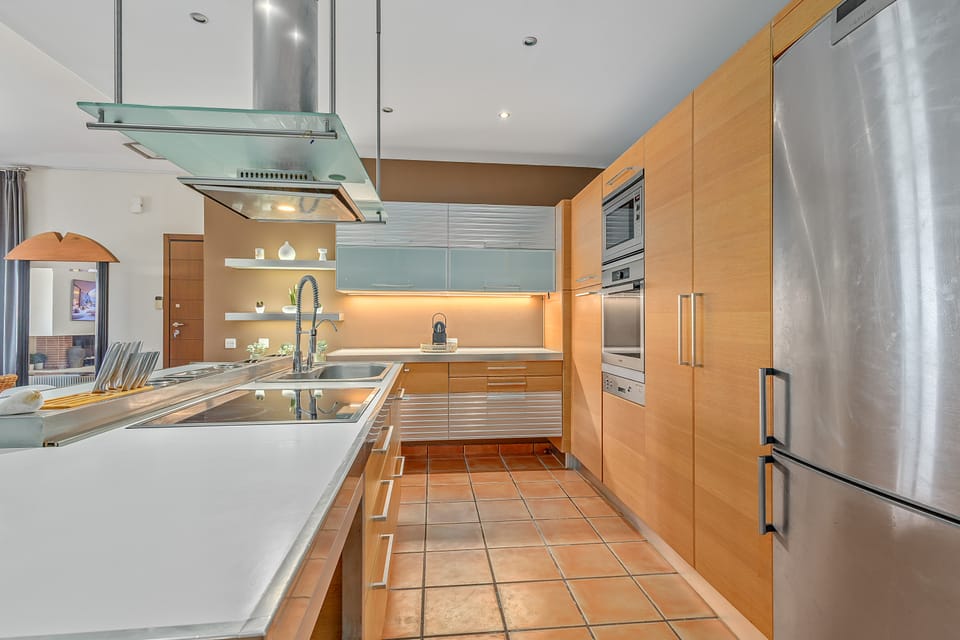 The Charis kitchen with stainless appliances, an island cooktop, and terracotta floors