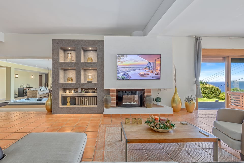 The Charis living room with a fireplace and glass doors to the sea-view terrace
