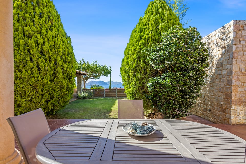 A Charis terrace dining table framed by cypress trees with sea and hill views
