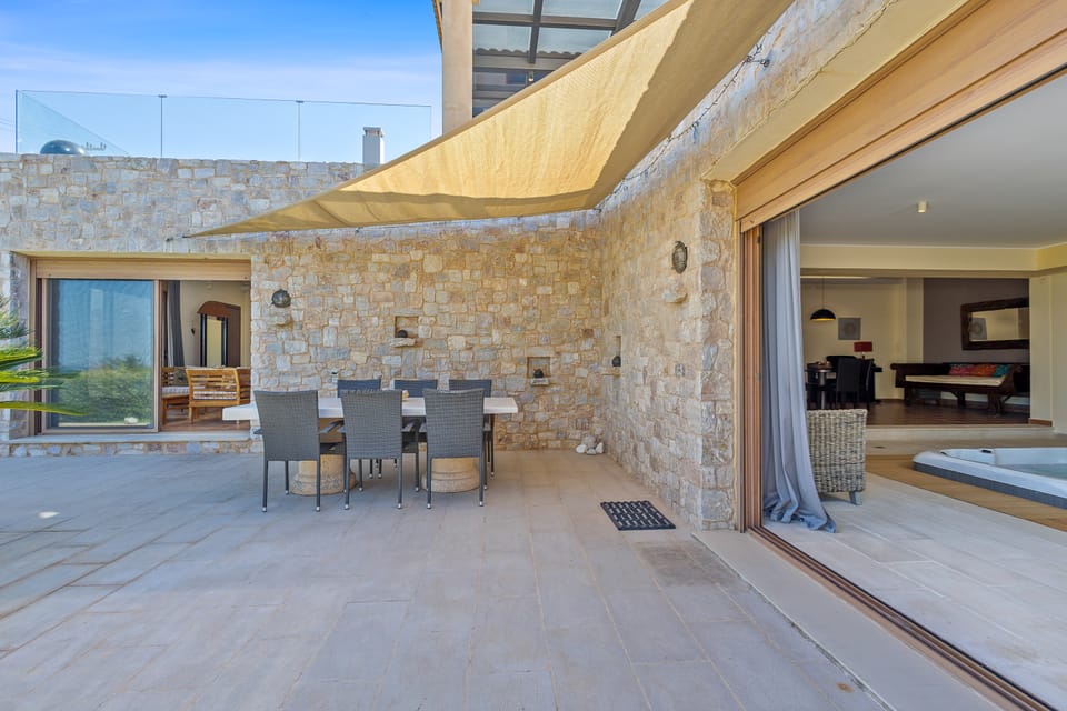 The Charis shaded stone terrace with outdoor dining under a cream shade sail