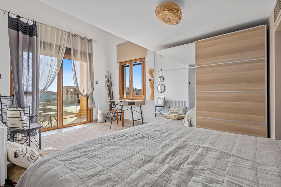 A ground-floor Kleos suite with a writing desk, mirrored wardrobe, and balcony