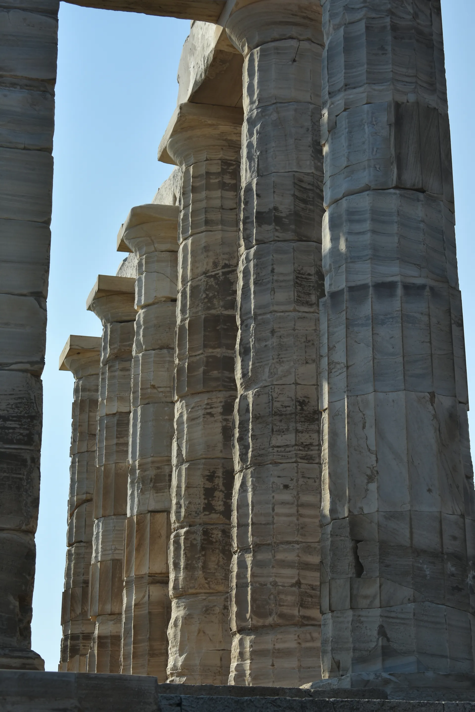 Low-angle view up the weathered Doric columns of the Temple of Poseidon in daylight