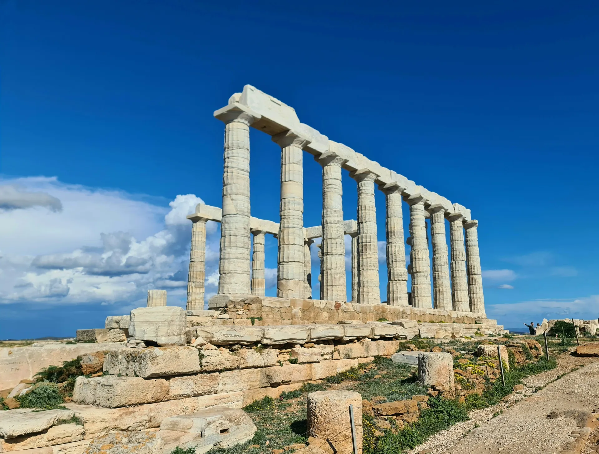 The Temple of Poseidon colonnade on its rocky headland under a bright blue sky