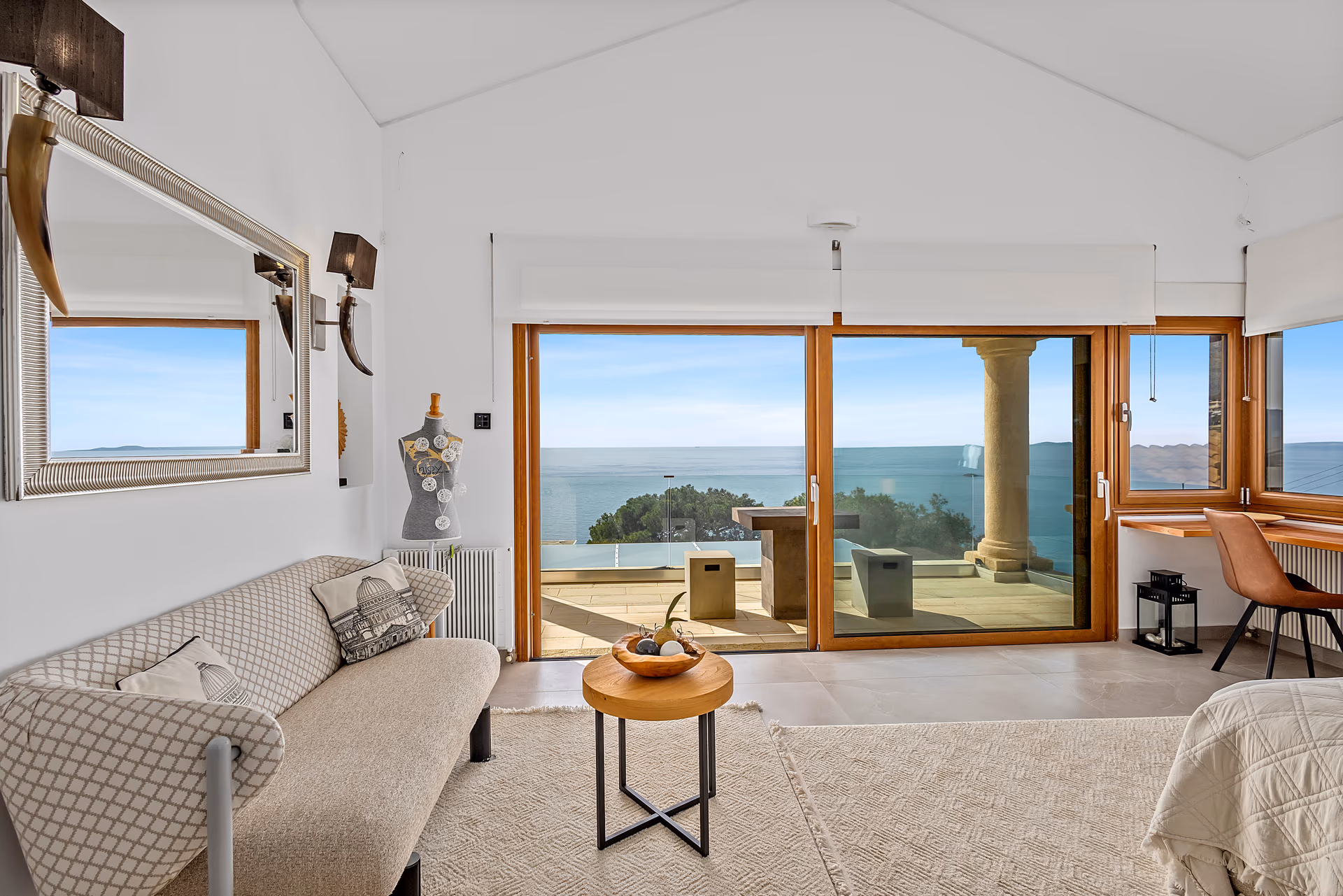 A top-floor View House suite opening through sliding doors to a private terrace and the Saronic Gulf